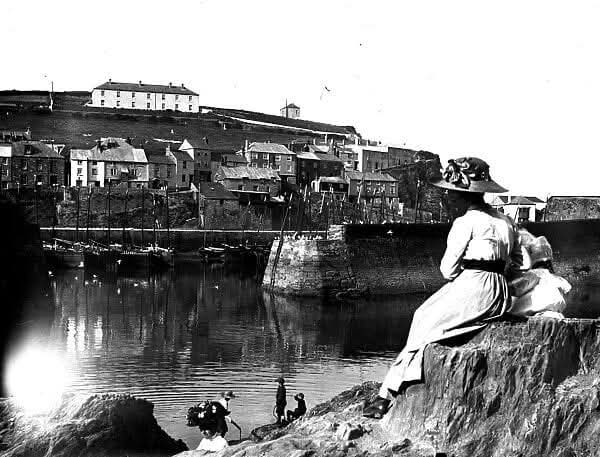 Woman and child overlooking Mevagissey harbour Cornwall early 1900s fishing village scene