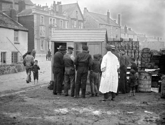 Fishermen and traders gathered around Pawlyn Bros fish crates, illustrating the historic Cornish fish trade
