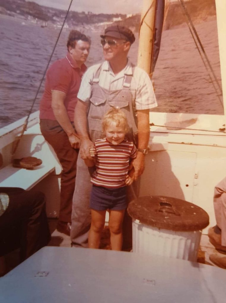 Mevagissey fisherman Hainsley Hunkin holding a child on a fishing boat